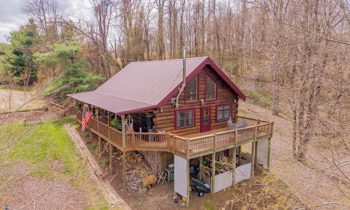 Floyd House | Peaceful log cabin retreat with wraparound deck, open living space, full kitchen, cozy bedrooms & scenic wooded views.